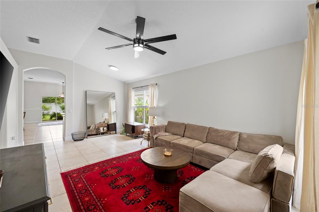 A living room features a large red area rug, a sectional sofa, and a ceiling fan — 6222 BLUEFLOWER COURT, BRADENTON, FL