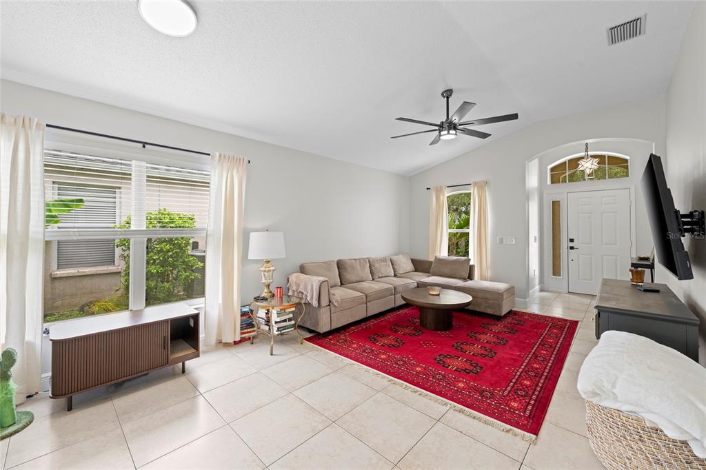 A living room features a beige sectional sofa, a red area rug, and tile flooring — 6222 BLUEFLOWER COURT, BRADENTON, FL