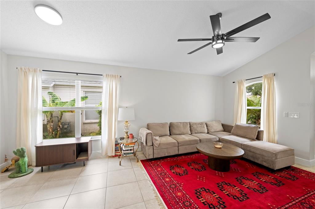 A living room features a beige sectional sofa, a red patterned rug, and a ceiling fan — 6222 BLUEFLOWER COURT, BRADENTON, FL