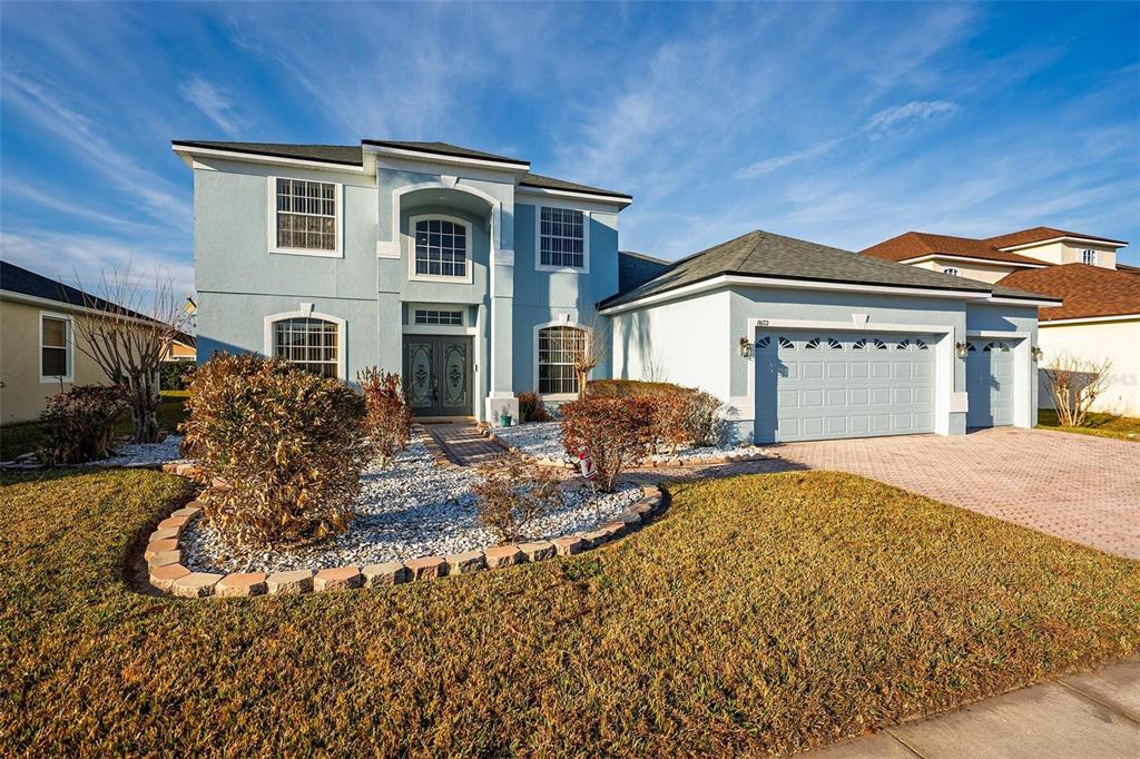 A two-story light blue house with a paved driveway and a landscaped front yard — 18172 THORNHILL GRAND CIRCLE, ORLANDO, FL