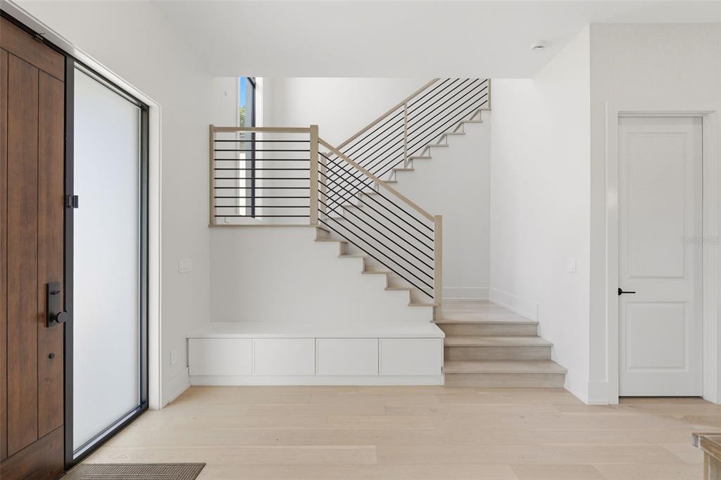 A modern entryway features a wooden front door, a built-in bench, and a floating staircase — 809 E CHURCH STREET, ORLANDO, FL