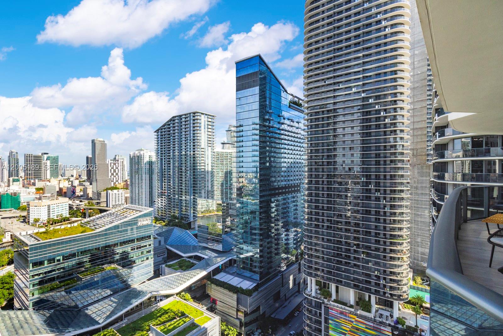 An elevated view of a modern city skyline featuring several glass skyscrapers and green rooftops — 55 SW 9th St # 3010, Miami FL 33130, MIAMI, FL