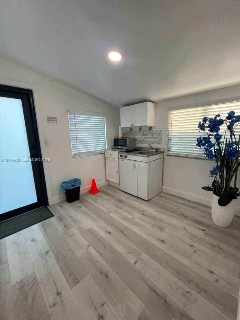 A small kitchen area features white cabinets, a sink, a microwave, and light wood flooring — 5615 Hope St # 1, Hollywood FL 33021, HOLLYWOOD, FL