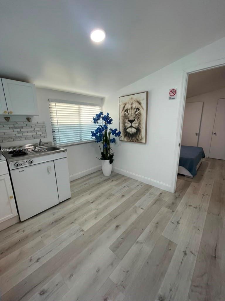 A small kitchen area features white cabinetry, a sink, and light wood-look flooring — 5615 Hope St # 1, Hollywood FL 33021, HOLLYWOOD, FL