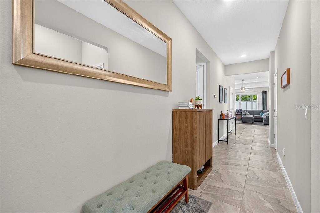 A hallway features a tufted bench, a wooden cabinet, and a mirror on the wall — 2044 CANOPY TERRACE BOULEVARD, DELAND, FL