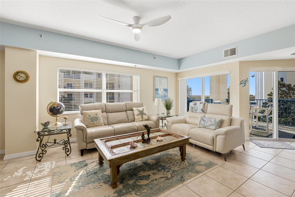 A living room features light tile flooring, a beige sofa set, and a ceiling fan — 5300 S ATLANTIC AVENUE UNIT 9-401, NEW SMYRNA BEACH, FL