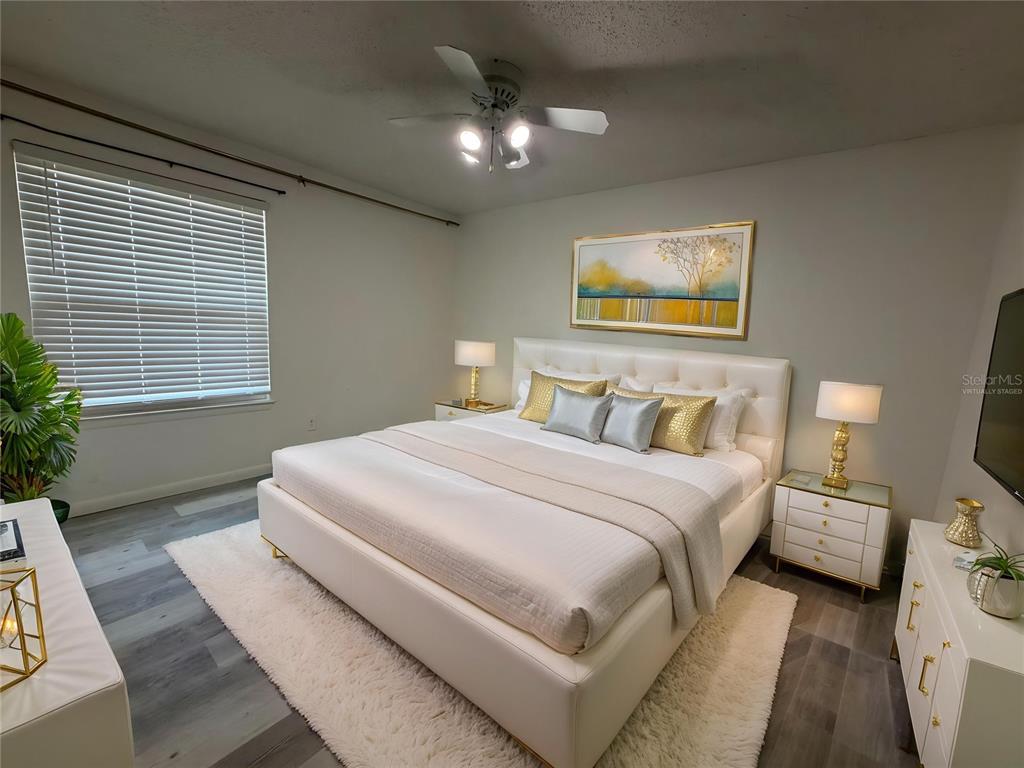 A bedroom features a white tufted bed, two nightstands, a ceiling fan, and gray flooring — 3756 IDLEBROOK CIRCLE UNIT 108, CASSELBERRY, FL