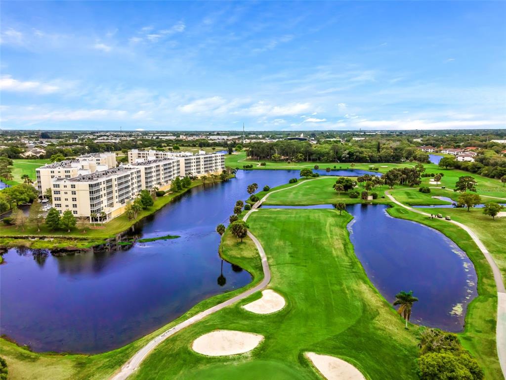 An aerial view shows a large apartment building situated beside a golf course and lake — 1200 COUNTRY CLUB DRIVE UNIT 5506, LARGO, FL