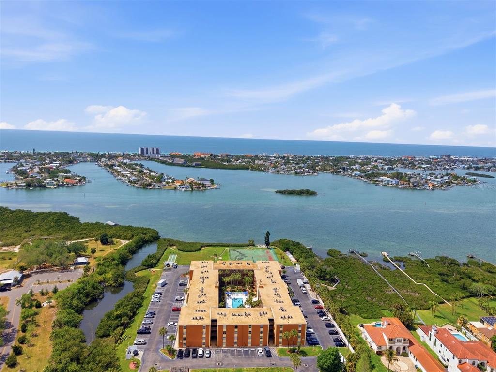 An aerial view shows a multi-story apartment complex surrounded by water and coastal vegetation — 12760 INDIAN ROCKS ROAD UNIT 1082, LARGO, FL