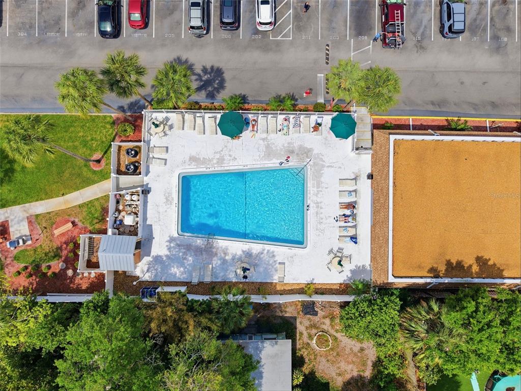 An aerial view shows a rectangular swimming pool surrounded by a patio, lounge chairs, and landscaping — 12760 INDIAN ROCKS ROAD UNIT 1082, LARGO, FL