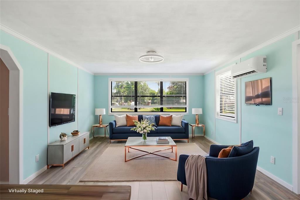 A virtually staged living room features light blue walls, a navy sofa, and wood-look flooring — 951 CR 453, LAKE PANASOFFKEE, FL