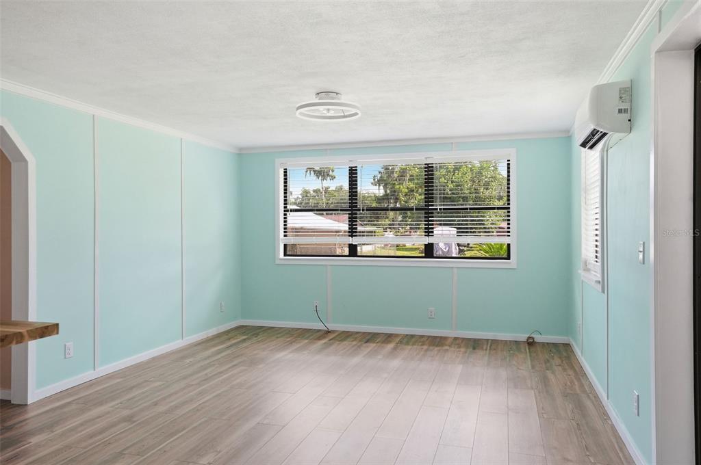 An empty room with light blue walls, wood-look flooring, a large window, and ceiling light — 951 CR 453, LAKE PANASOFFKEE, FL