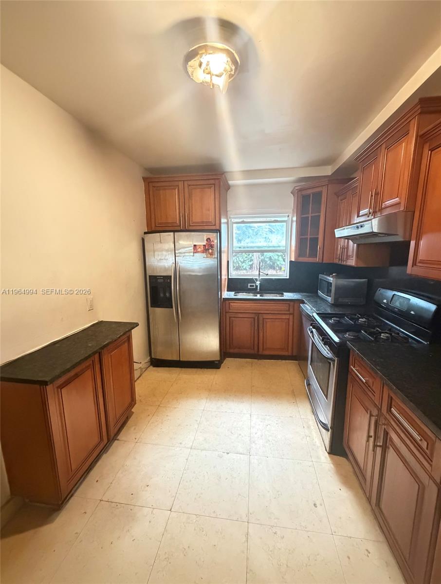 A kitchen features wood cabinets, stainless steel appliances, and dark countertops on a tiled floor — 2141 NE 124th St, North Miami FL 33181, NORTH MIAMI, FL