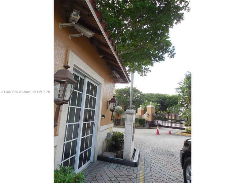 A view of a gated community entrance with a security camera and a lantern — 2173 Renaissance Blvd # 103, Miramar FL 33025, MIRAMAR, FL