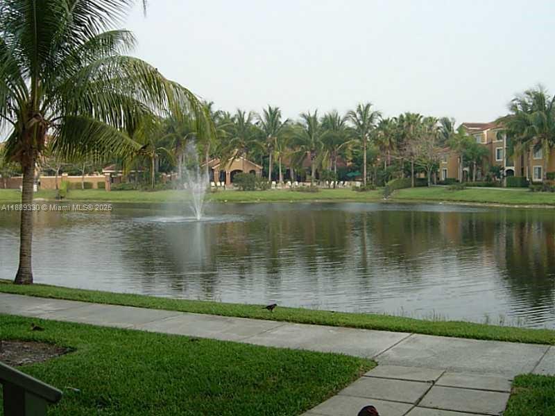 A view of a pond with a fountain, palm trees, and apartment buildings in the background — 2173 Renaissance Blvd # 103, Miramar FL 33025, MIRAMAR, FL