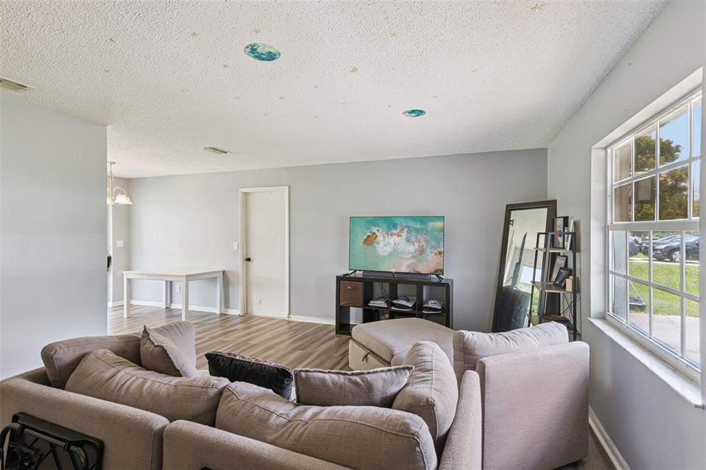 An empty living room features light gray walls, wood-look flooring, a window, and a closet — 2162 SWANSON DRIVE, DELTONA, FL
