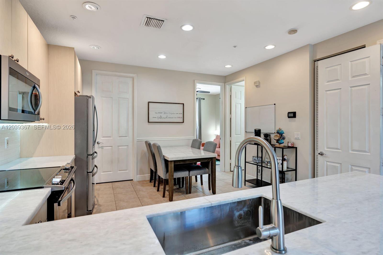A kitchen with marble countertops, stainless steel appliances, and a dining area in the background — 112 Osceola Ln, Jupiter FL 33458, JUPITER, FL