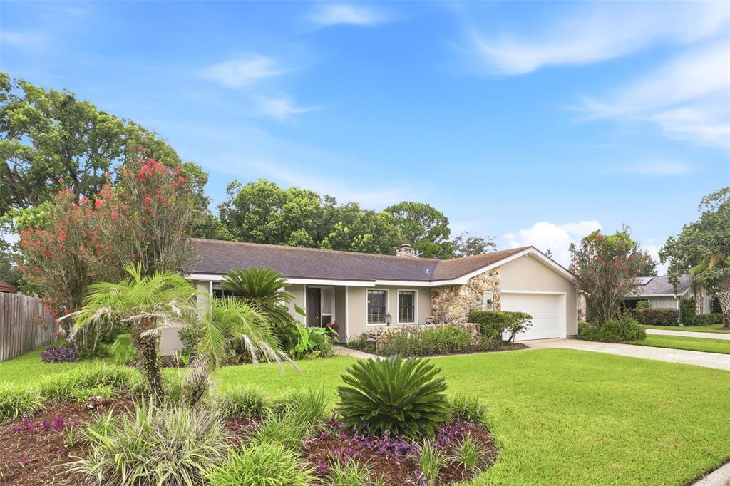 A single-story house with a stone facade, a two-car garage, and a landscaped front yard — 207 ATHERSTONE COURT, LONGWOOD, FL