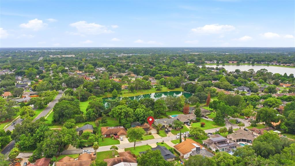 An aerial view shows a residential neighborhood with houses, trees, and a small lake — 207 ATHERSTONE COURT, LONGWOOD, FL