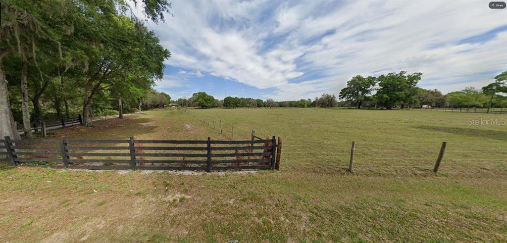 A fenced, grassy pasture with scattered trees under a partly cloudy sky — GREEN POND RD, POLK CITY, FL