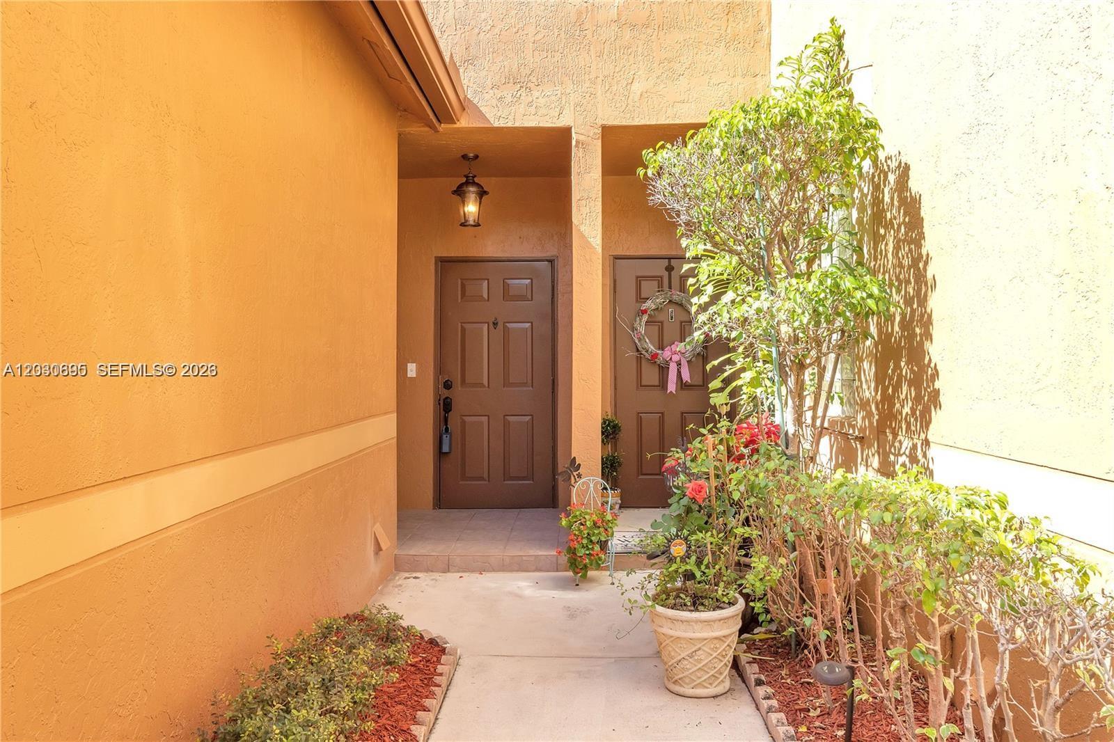 The exterior entrance features two brown doors, a concrete walkway, and potted plants — 1393 Barcelona Way # 26, Weston FL 33327, WESTON, FL
