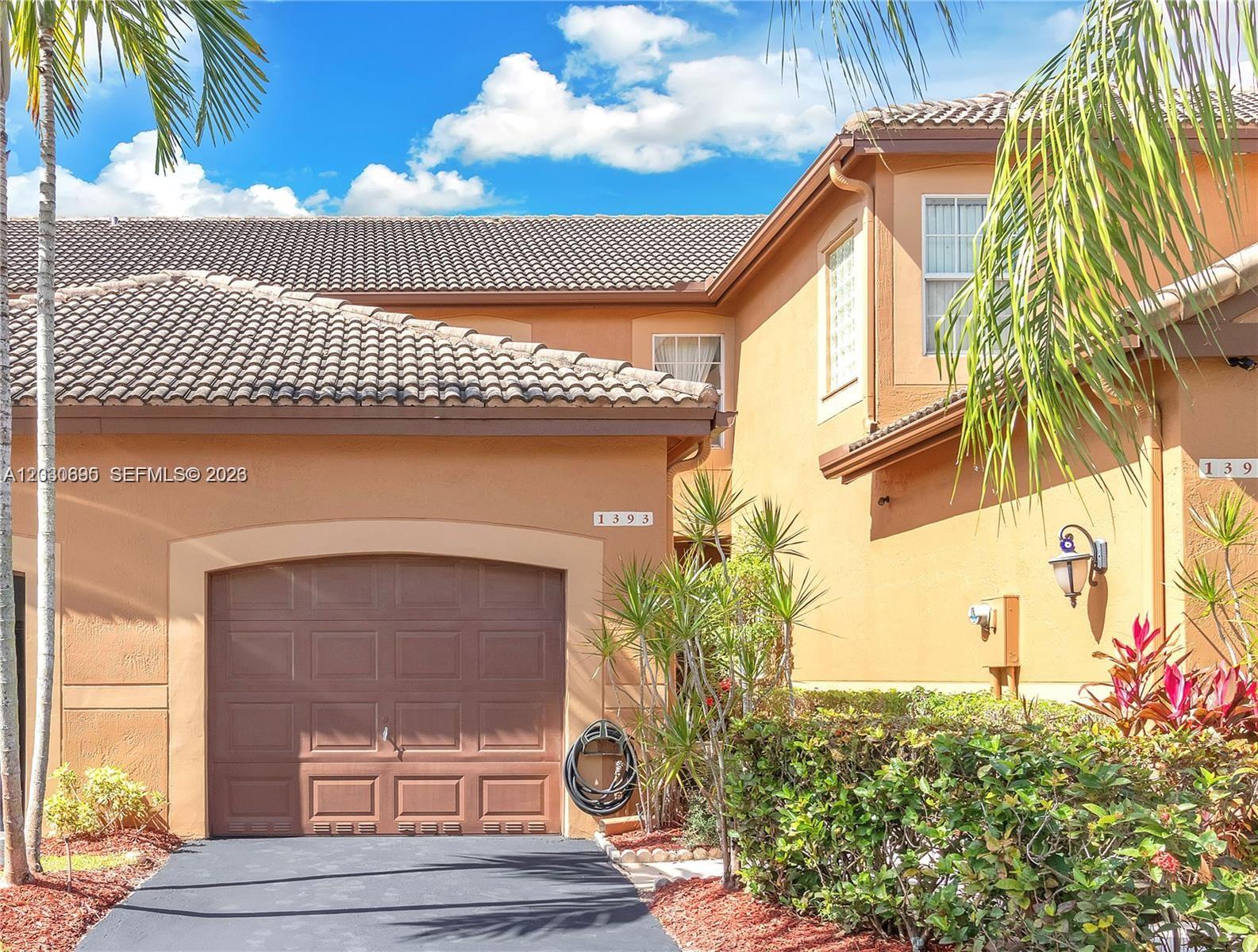 The exterior of a two-story stucco house features a brown garage door and tile roof — 1393 Barcelona Way # 26, Weston FL 33327, WESTON, FL