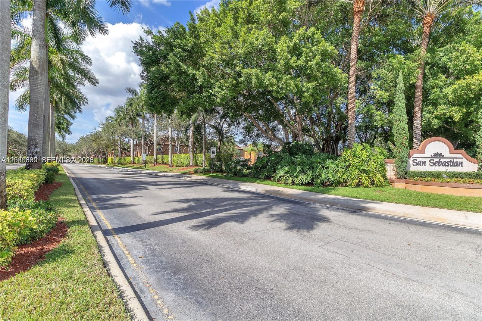 A street view shows a lushly landscaped entrance sign for San Sebastian with palm trees — 1393 Barcelona Way # 26, Weston FL 33327, WESTON, FL
