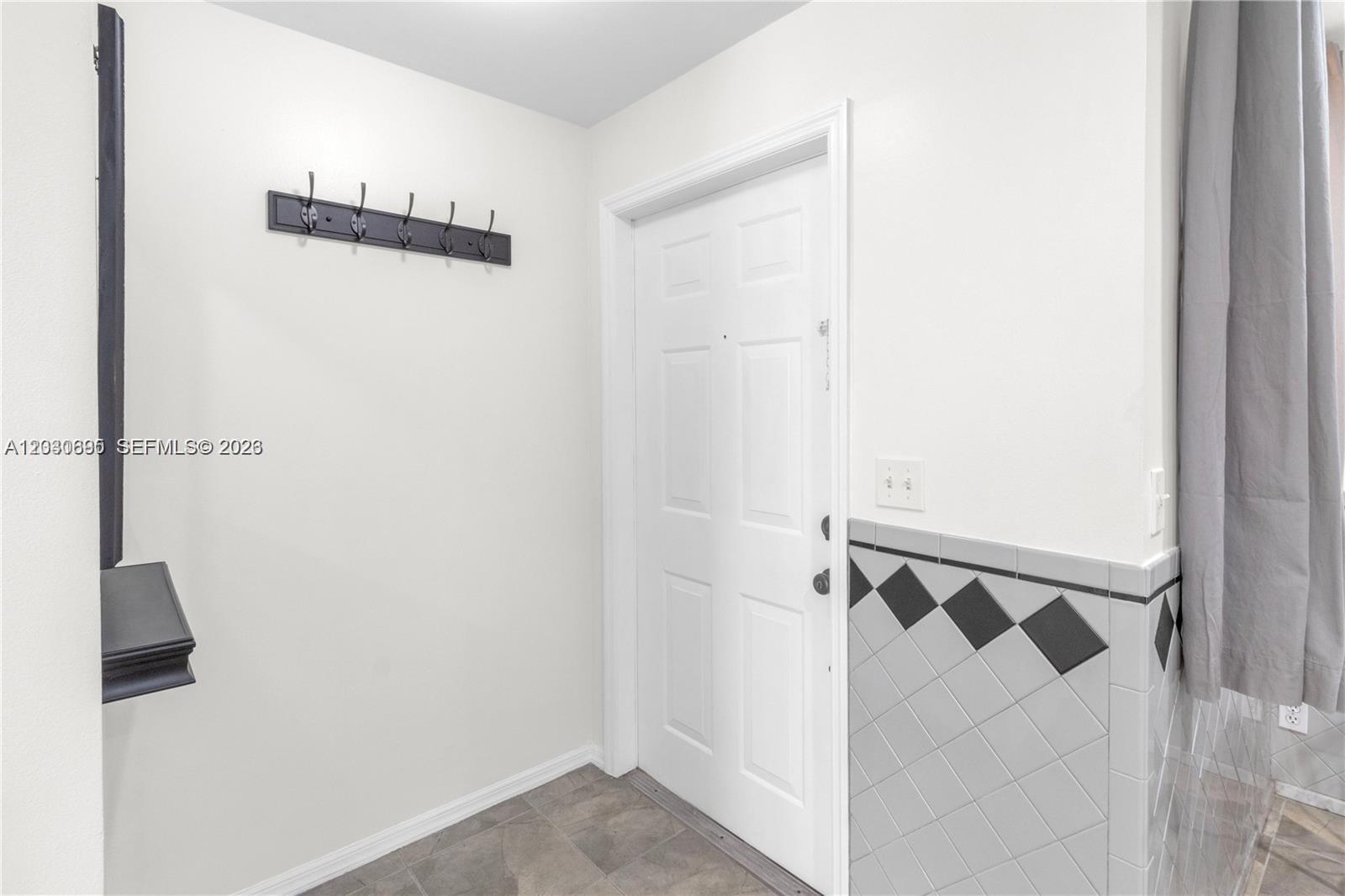 An entryway features a white door, a coat rack, and a tiled lower wall section — 1393 Barcelona Way # 26, Weston FL 33327, WESTON, FL
