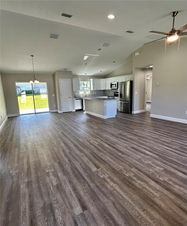 An open-concept kitchen and living area feature wood-look flooring, white cabinetry, and a center island — 15613 SE 84TH TERRACE, SUMMERFIELD, FL