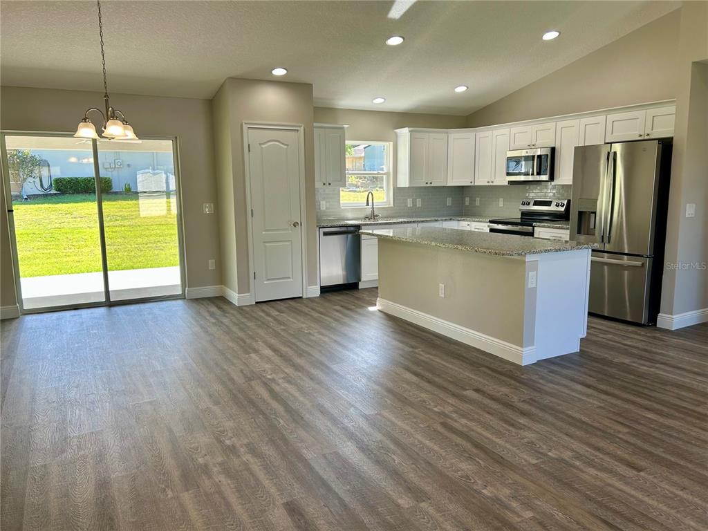 A kitchen with white cabinets, stainless steel appliances, and an island opens to a yard — 15613 SE 84TH TERRACE, SUMMERFIELD, FL