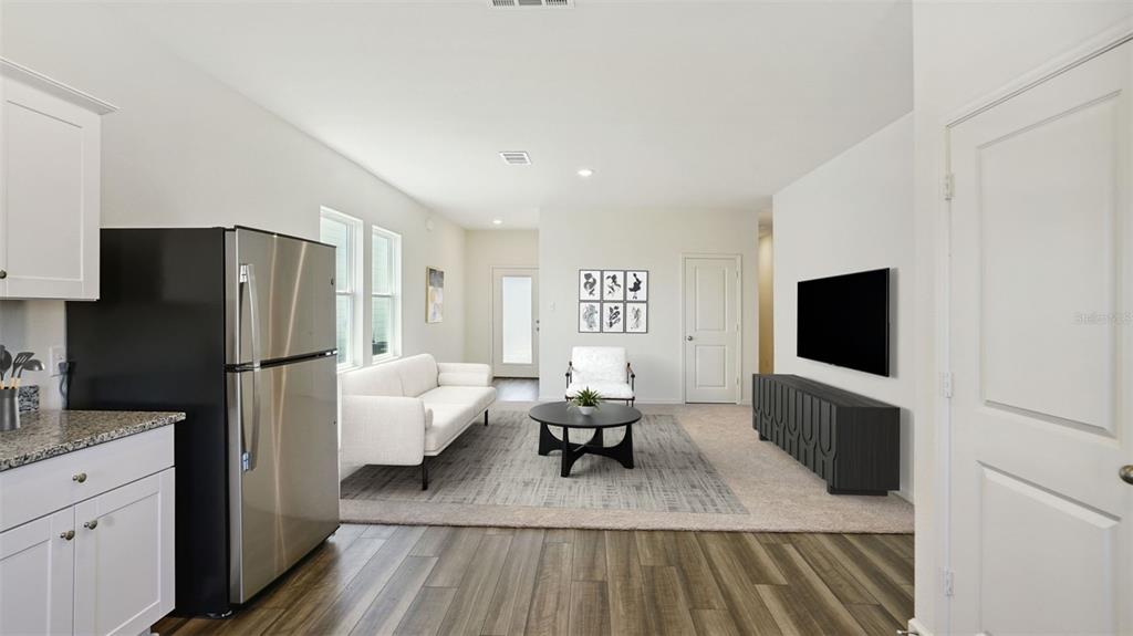 This living room features a white sofa, a black coffee table, and a wall-mounted television — 5859 KALAMATA DRIVE, POLK CITY, FL