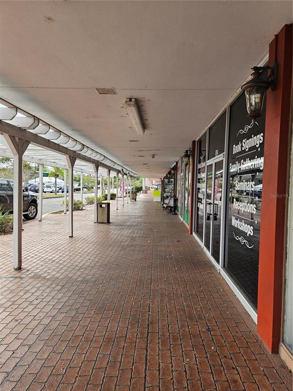 A covered brick walkway runs alongside a storefront with glass doors and windows — 2921 S ORLANDO DRIVE UNIT 144, SANFORD, FL