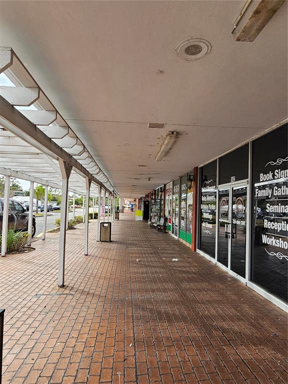 A covered brick walkway runs alongside a row of storefronts with glass doors and windows — 2921 S ORLANDO DRIVE UNIT 144, SANFORD, FL