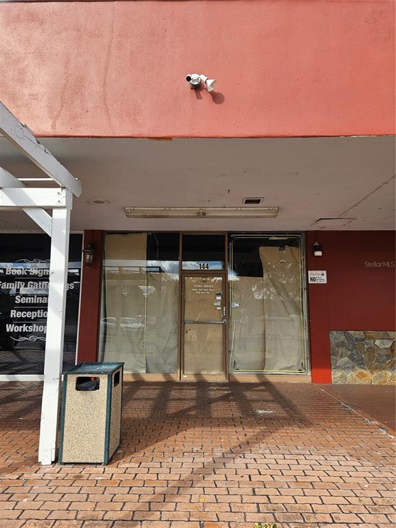 The exterior of a commercial storefront features a brick walkway, glass doors, and red walls — 2921 S ORLANDO DRIVE UNIT 144, SANFORD, FL