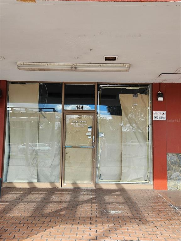 The exterior of a commercial storefront features a glass door and windows covered by paper — 2921 S ORLANDO DRIVE UNIT 144, SANFORD, FL