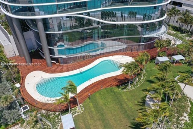 An aerial view shows a curved swimming pool surrounded by a wooden deck and lawn — 15701 E COLLINS # 1403, Sunny Isles Beach FL 33160, SUNNY ISLES BEACH, FL