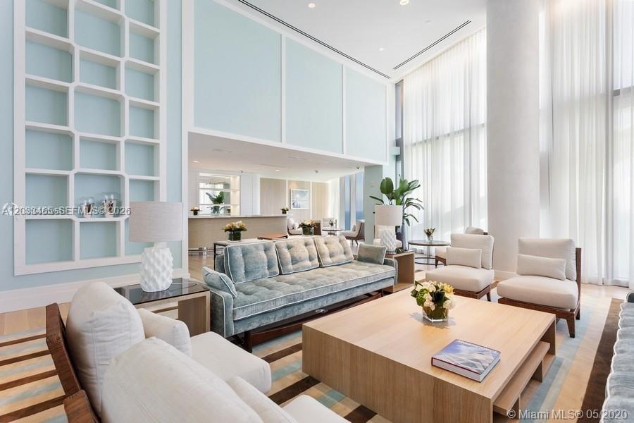 A spacious, high-ceilinged living room features light blue walls, a large sofa, and wood furniture — 15701 E COLLINS # 1403, Sunny Isles Beach FL 33160, SUNNY ISLES BEACH, FL