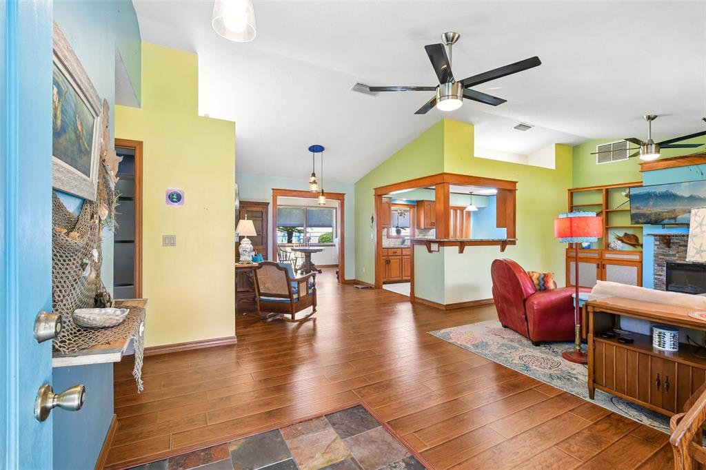 An open-concept living area features wood-look flooring, vaulted ceilings, and a kitchen with wood cabinetry — 58 BRITTANY LANE, PALM COAST, FL