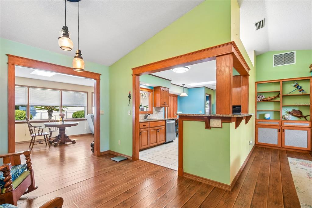 A living area with wood floors, green walls, and an open kitchen with wooden cabinets — 58 BRITTANY LANE, PALM COAST, FL