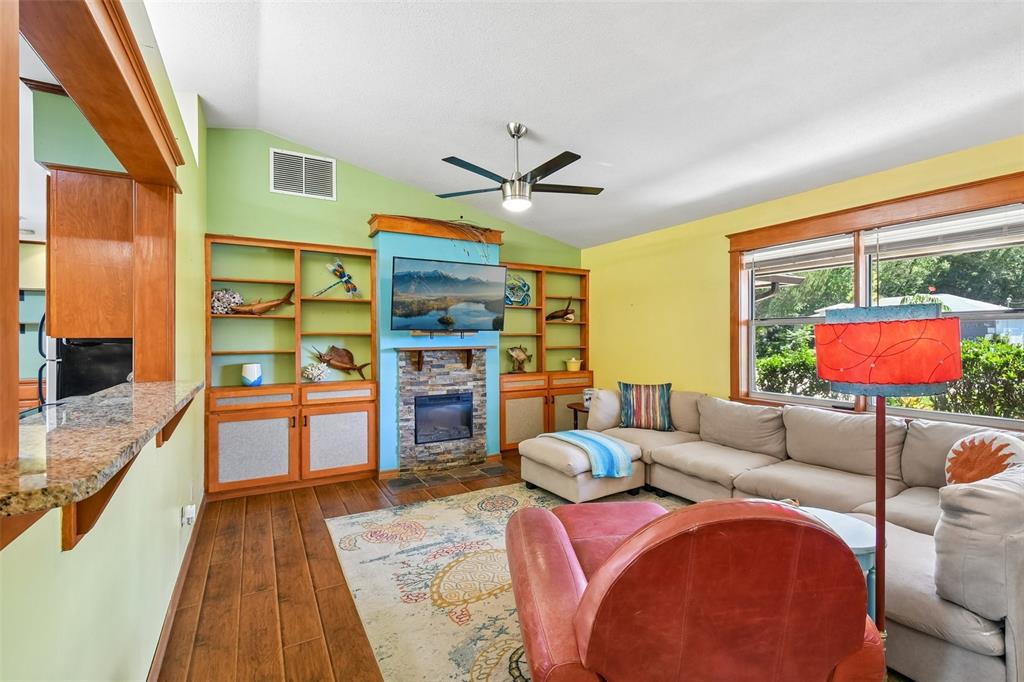 A living room features a stone fireplace, built-in shelving, a sectional sofa, and hardwood floors — 58 BRITTANY LANE, PALM COAST, FL