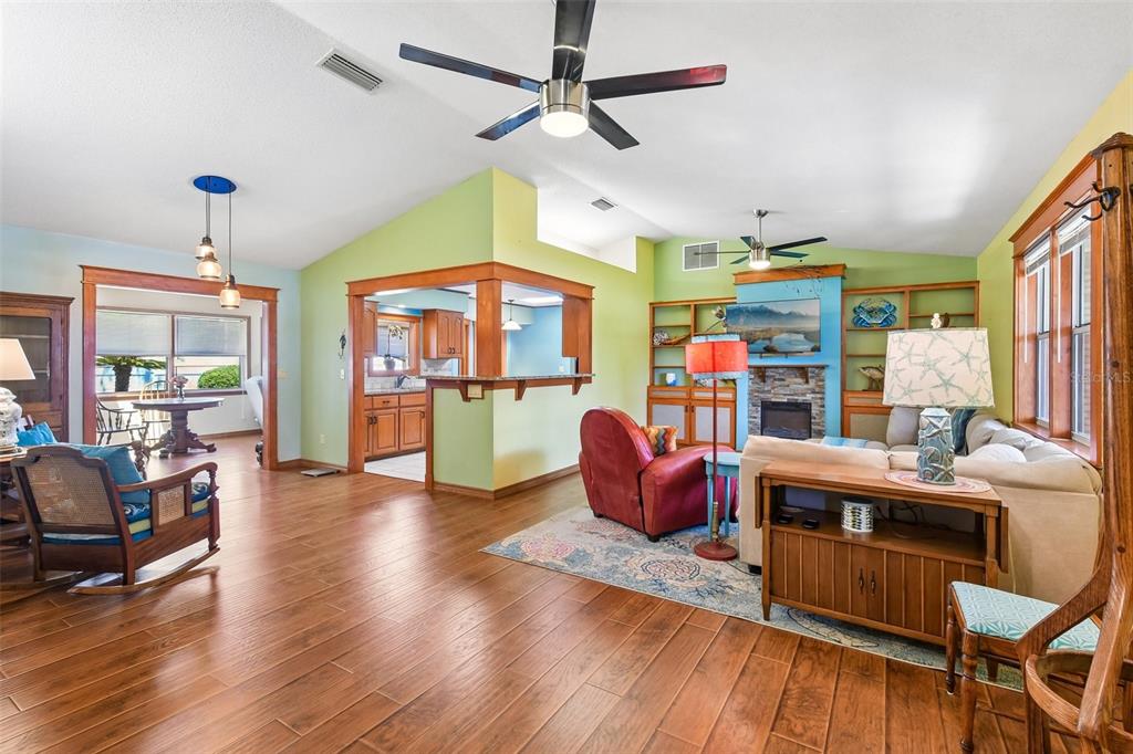 A living room features wood floors, a fireplace, a ceiling fan, and an open kitchen — 58 BRITTANY LANE, PALM COAST, FL
