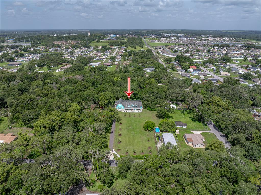 An aerial view shows a teal house with a large yard surrounded by dense trees — 7427 20TH STREET, ZEPHYRHILLS, FL