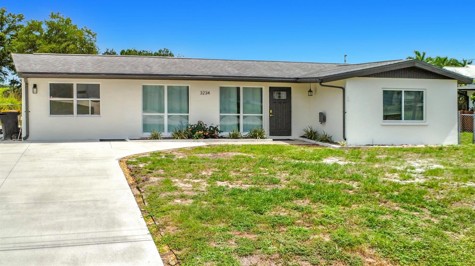 A single-story white house with a dark roof, front door, and a concrete driveway — 3234 Daytona Drive, Punta Gorda FL 33983, PUNTA GORDA, FL