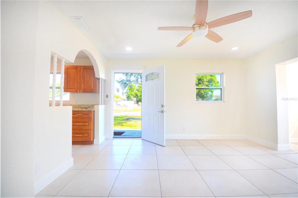 A bright living room with tile floors, a ceiling fan, and an open front door — 8307 LIBBY LANE, TAMPA, FL