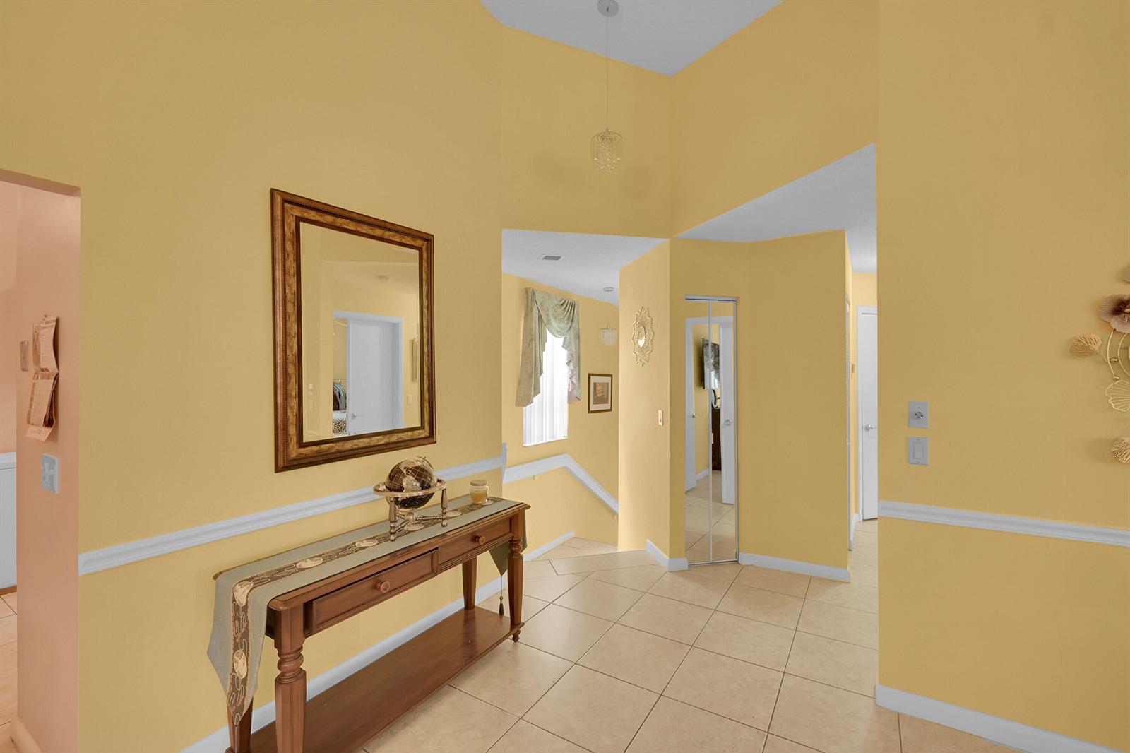 A foyer with yellow walls, tile flooring, a wooden console table, and a mirror — 5379 Verona Drive # H, Boynton Beach FL 33437, BOYNTON BEACH, FL