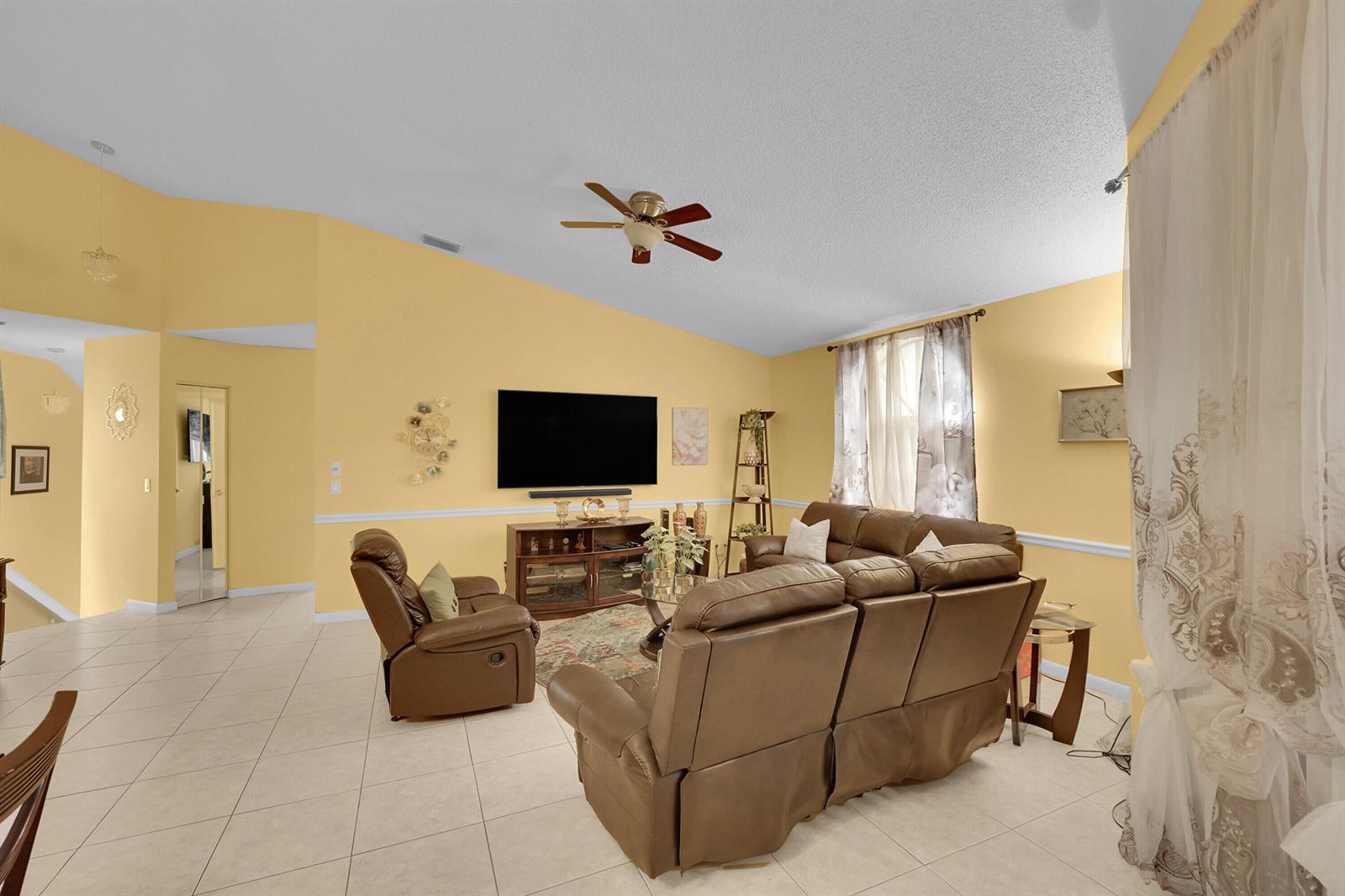 A living room with yellow walls, tile flooring, a vaulted ceiling, and brown leather furniture — 5379 Verona Drive # H, Boynton Beach FL 33437, BOYNTON BEACH, FL
