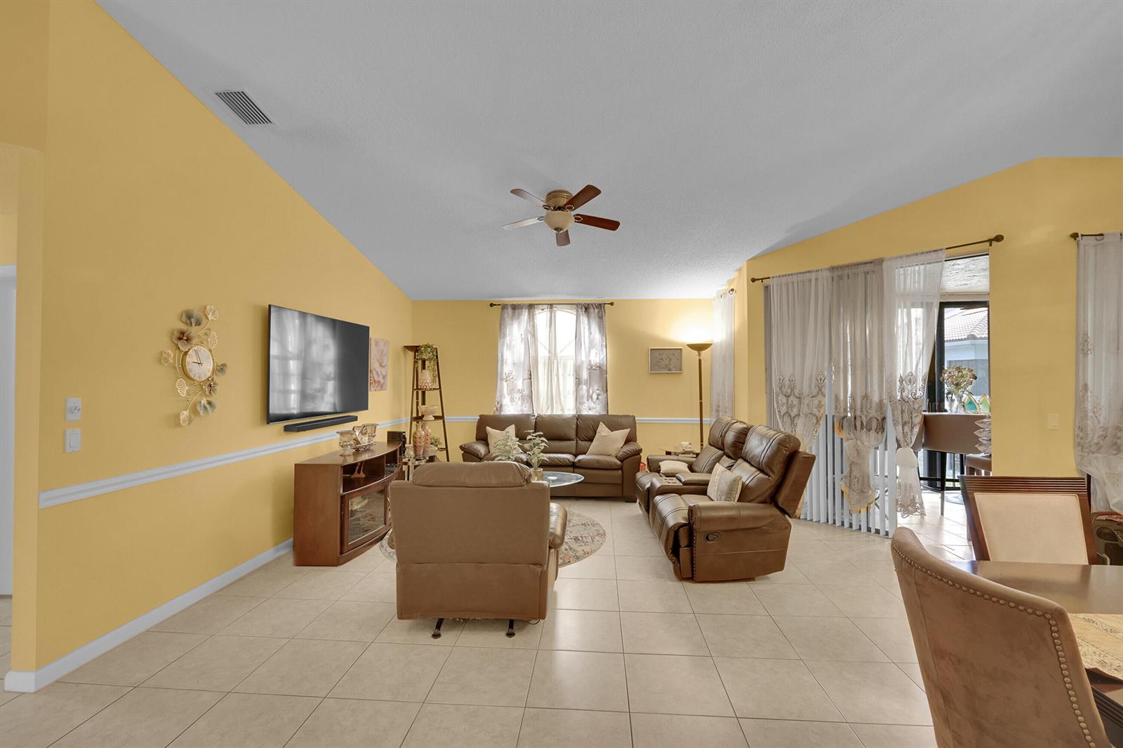 A living room with yellow walls, tile floors, brown leather furniture, and a ceiling fan — 5379 Verona Drive # H, Boynton Beach FL 33437, BOYNTON BEACH, FL