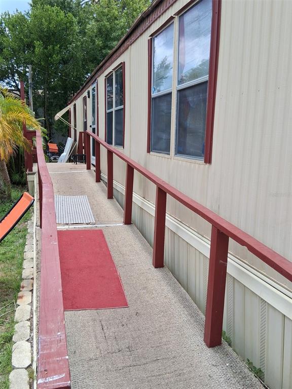 A long, outdoor wheelchair ramp with red wooden railings leads to a mobile home entrance — 1804 DOROTHY BOULEVARD UNIT 403, LUTZ, FL