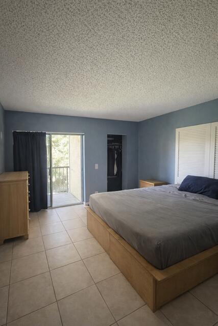 A bedroom with blue walls, tile flooring, a platform bed, and a sliding glass door — 416 Meadows Circle, Boynton Beach FL 33436, BOYNTON BEACH, FL