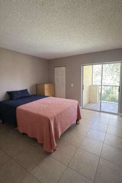 A bedroom with tile flooring, a bed, a dresser, and a sliding glass door to a balcony — 416 Meadows Circle, Boynton Beach FL 33436, BOYNTON BEACH, FL